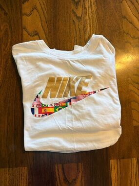 Nike White Short Sleeve Tee with Gold Logo and Multicolor Flag Swoosh Accent